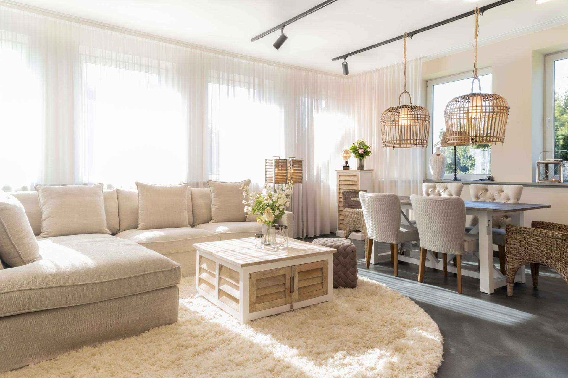 Modern eingerichtetes Wohnzimmer mit hellem Ecksofa, Couchtisch, Essbereich und dekorativen Lampen – FingerHome Interieur-Inspiration.