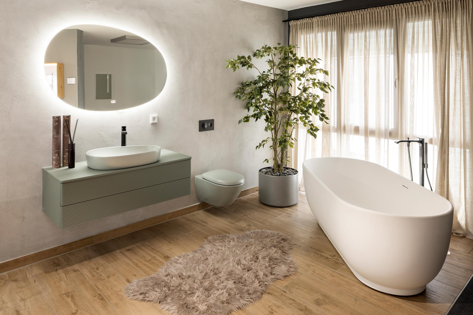 Modern gestaltetes Badezimmer mit freistehender Badewanne, großem Spiegel und stilvoller Einrichtung in der FingerHaus Ideenwelt Frankenberg.