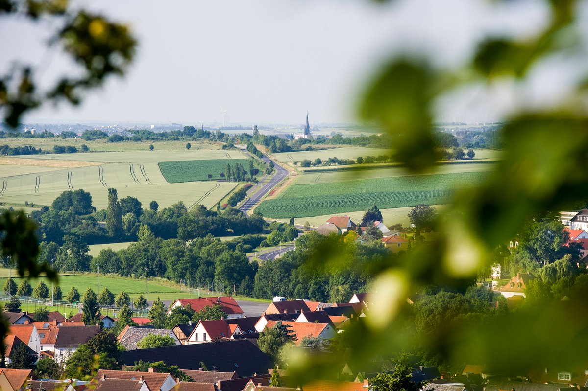 Blick über Bad Nauheim-Steinfurth mit roten Dächern, grünen Feldern und weiter Landschaft bis zum Horizont.